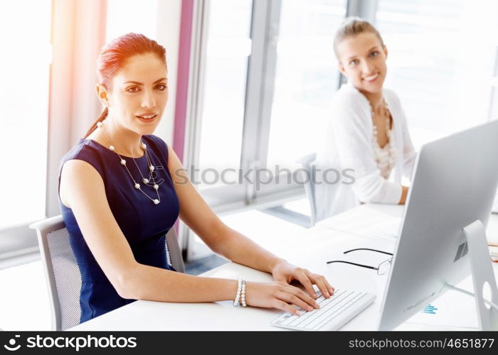 Attractive office worker sitting at desk. Attractive woman sitting at desk in office