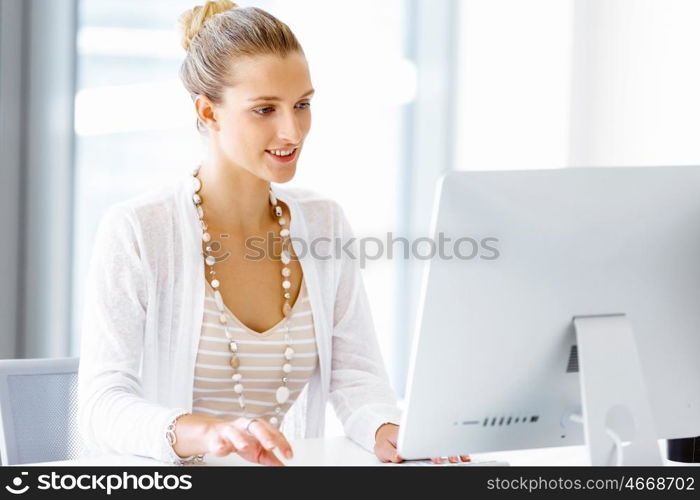 Attractive office worker sitting at desk. Attractive woman sitting at desk in office