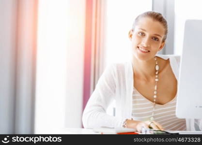 Attractive office worker sitting at desk. Attractive woman sitting at desk in office