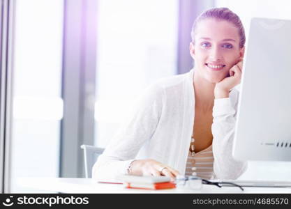 Attractive office worker sitting at desk. Attractive woman sitting at desk in office