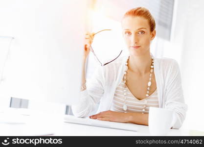 Attractive office worker sitting at desk. Attractive woman sitting at desk in office