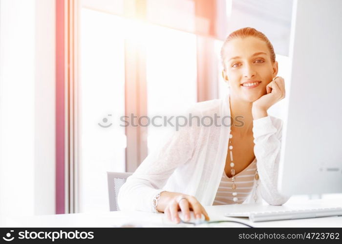 Attractive office worker sitting at desk. Attractive woman sitting at desk in office