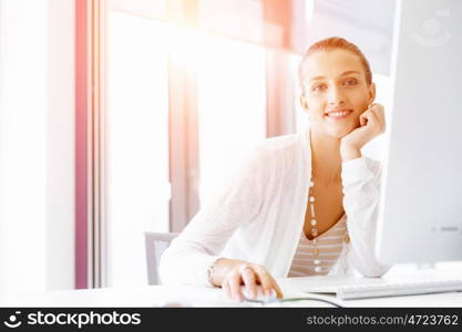 Attractive office worker sitting at desk. Attractive woman sitting at desk in office