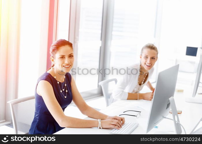 Attractive office worker sitting at desk. Attractive woman sitting at desk in office