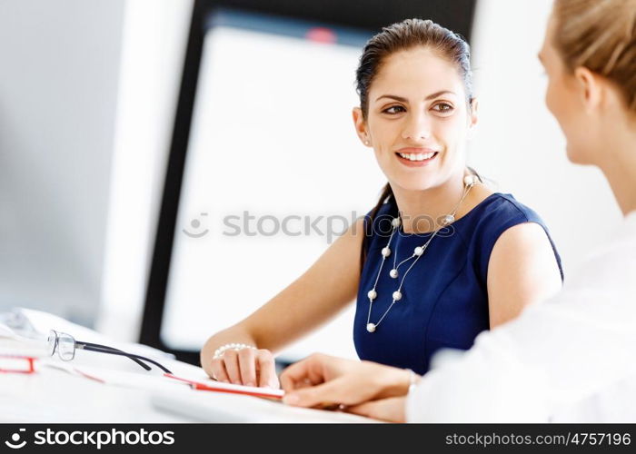 Attractive office worker sitting at desk. Attractive woman sitting at desk in office