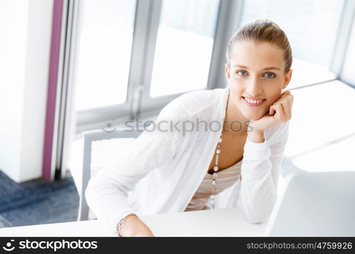 Attractive office worker sitting at desk. Attractive woman sitting at desk in office