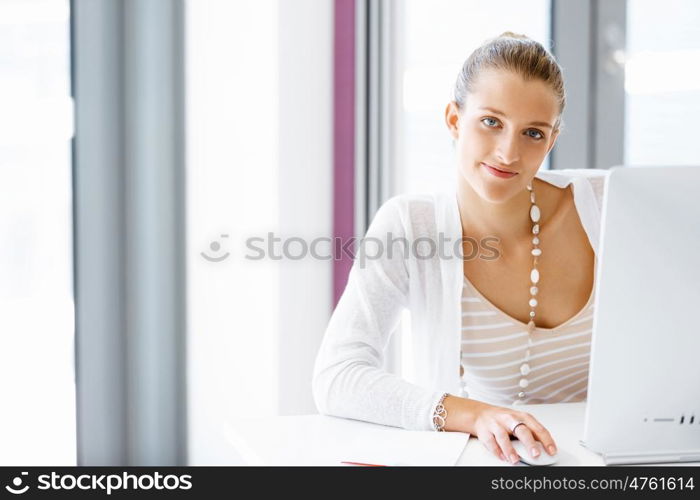 Attractive office worker sitting at desk. Attractive woman sitting at desk in office