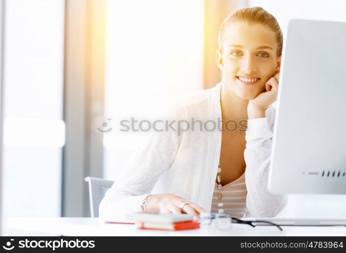 Attractive office worker sitting at desk. Attractive woman sitting at desk in office