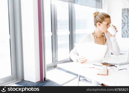 Attractive office worker sitting at desk. Attractive woman sitting at desk in office