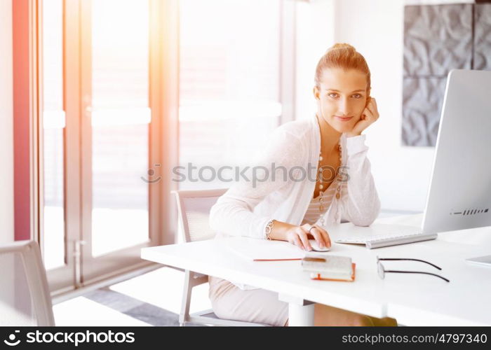 Attractive office worker sitting at desk. Attractive woman sitting at desk in office