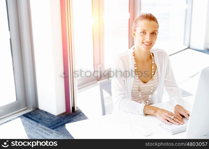 Attractive office worker sitting at desk. Attractive woman sitting at desk in office