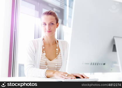 Attractive office worker sitting at desk. Attractive woman sitting at desk in office