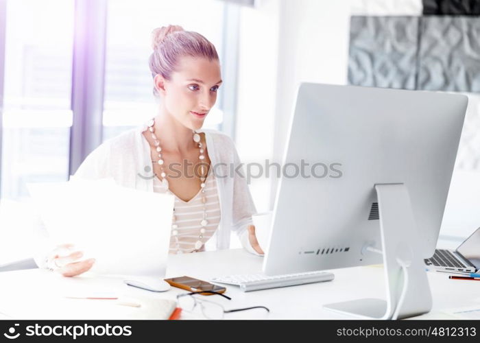 Attractive office worker sitting at desk. Attractive woman sitting at desk in office