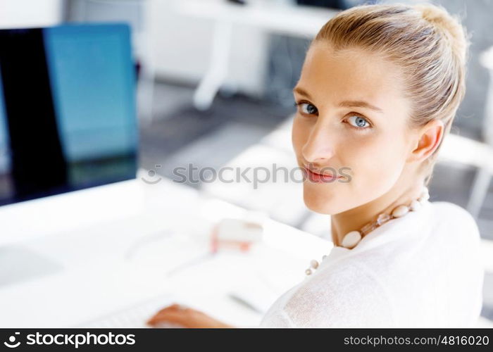 Attractive office worker sitting at desk. Attractive woman sitting at desk in office