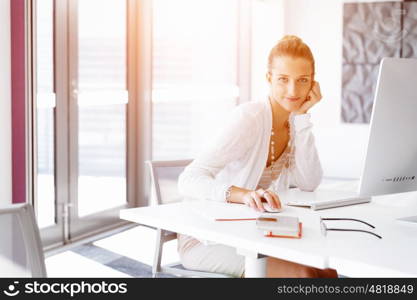 Attractive office worker sitting at desk. Attractive woman sitting at desk in office