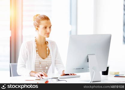 Attractive office worker sitting at desk. Attractive woman sitting at desk in office