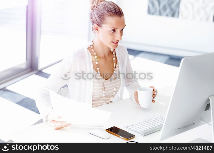 Attractive office worker sitting at desk. Attractive woman sitting at desk in office