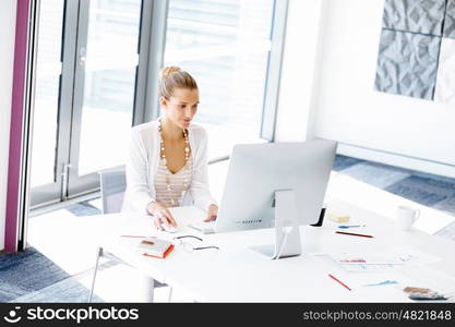 Attractive office worker sitting at desk. Attractive woman sitting at desk in office