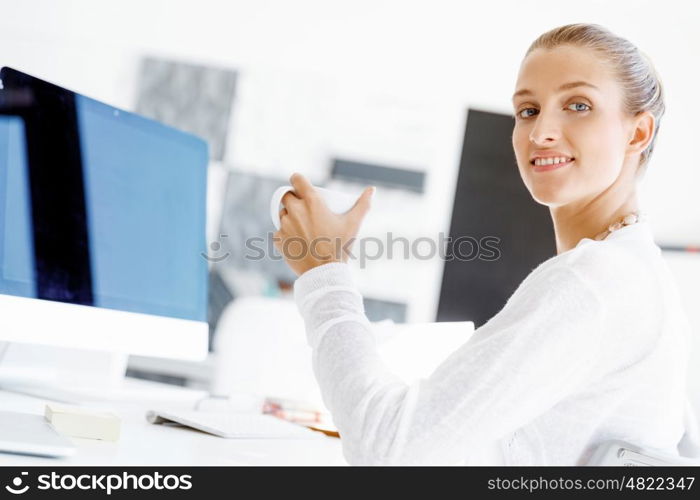 Attractive office worker sitting at desk. Attractive woman sitting at desk in office