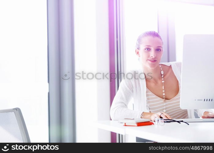 Attractive office worker sitting at desk. Attractive woman sitting at desk in office