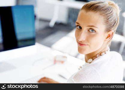 Attractive office worker sitting at desk. Attractive woman sitting at desk in office