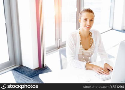 Attractive office worker sitting at desk. Attractive woman sitting at desk in office