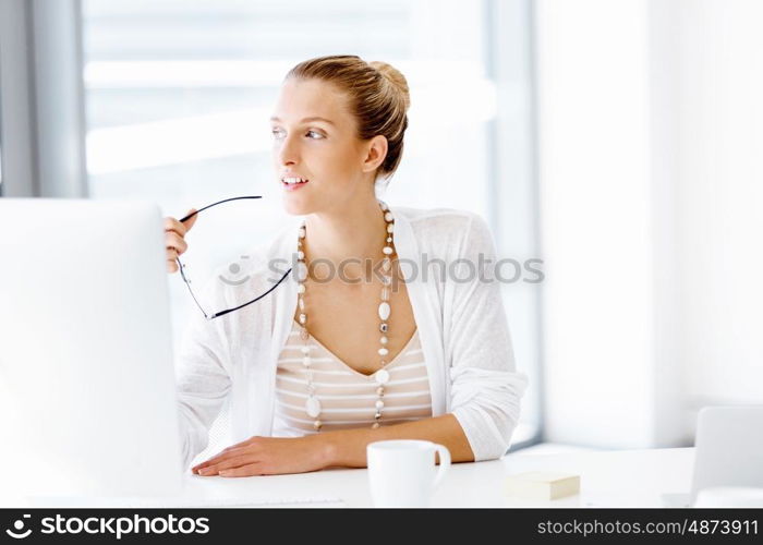 Attractive office worker sitting at desk. Attractive woman sitting at desk in office