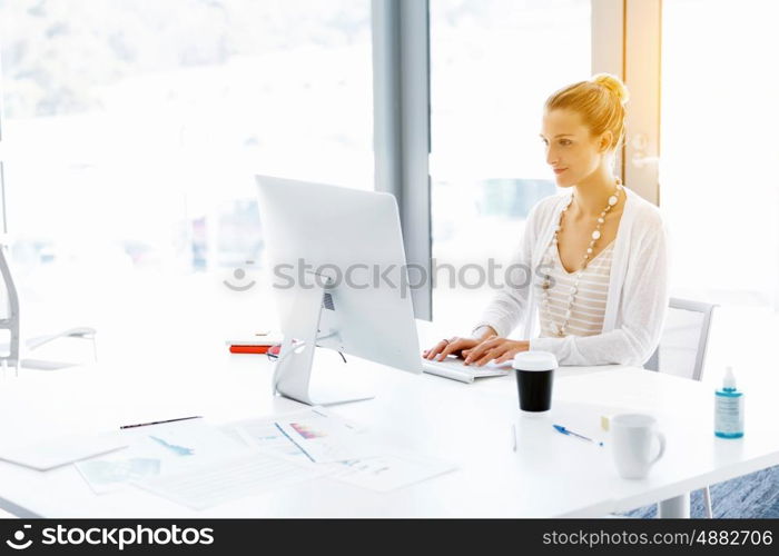 Attractive office worker sitting at desk. Attractive woman sitting at desk in office