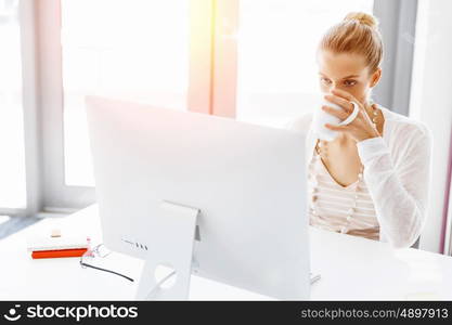 Attractive office worker sitting at desk. Attractive woman sitting at desk in office