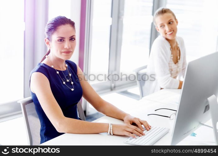 Attractive office worker sitting at desk. Attractive woman sitting at desk in office