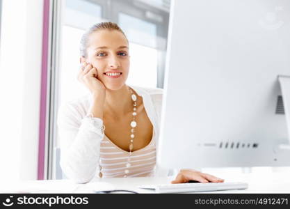 Attractive office worker sitting at desk. Attractive woman sitting at desk in office