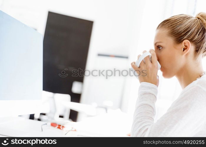 Attractive office worker sitting at desk. Attractive woman sitting at desk in office