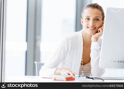 Attractive office worker sitting at desk. Attractive woman sitting at desk in office