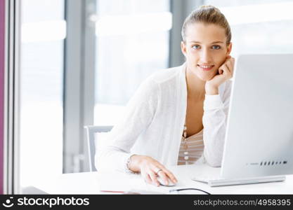 Attractive office worker sitting at desk. Attractive woman sitting at desk in office