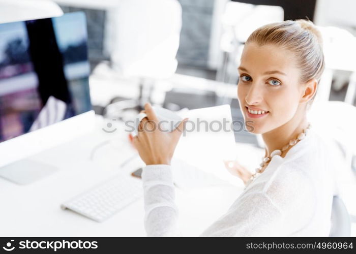 Attractive office worker sitting at desk. Attractive woman sitting at desk in office