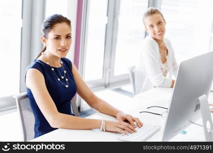 Attractive office worker sitting at desk. Attractive woman sitting at desk in office