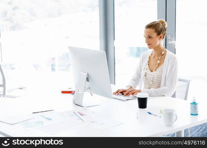 Attractive office worker sitting at desk. Attractive woman sitting at desk in office