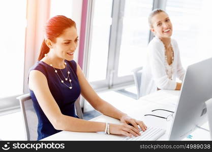 Attractive office worker sitting at desk. Attractive woman sitting at desk in office