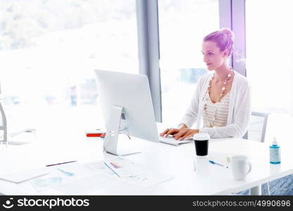 Attractive office worker sitting at desk. Attractive woman sitting at desk in office