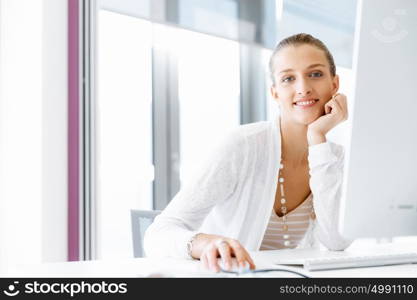 Attractive office worker sitting at desk. Attractive woman sitting at desk in office