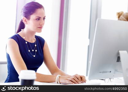 Attractive office worker sitting at desk. Attractive woman sitting at desk in office