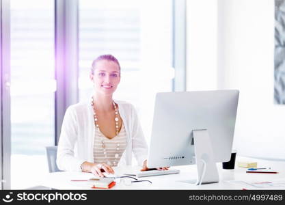 Attractive office worker sitting at desk. Attractive woman sitting at desk in office