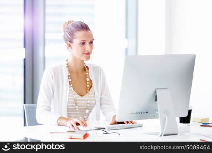 Attractive office worker sitting at desk. Attractive woman sitting at desk in office