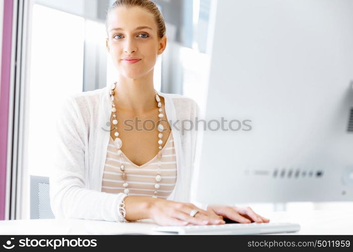 Attractive office worker sitting at desk. Attractive woman sitting at desk in office