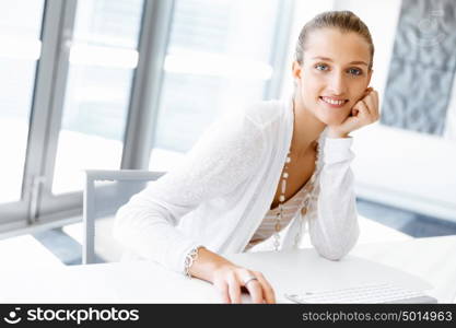 Attractive office worker sitting at desk. Attractive woman sitting at desk in office