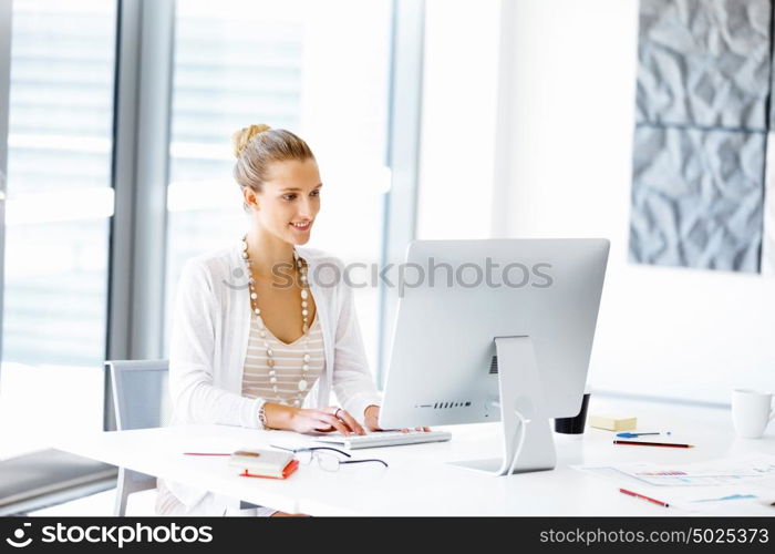 Attractive office worker sitting at desk. Attractive woman sitting at desk in office