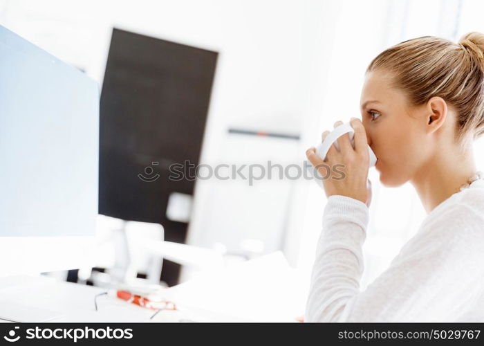 Attractive office worker sitting at desk. Attractive woman sitting at desk in office