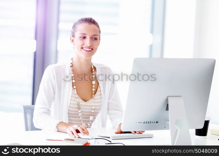 Attractive office worker sitting at desk. Attractive woman sitting at desk in office