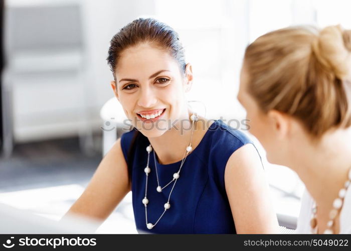 Attractive office worker sitting at desk. Attractive woman sitting at desk in office