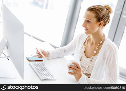 Attractive office worker sitting at desk. Attractive woman sitting at desk in office